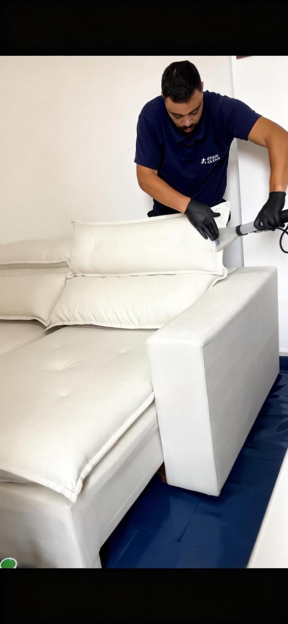 Profissional da Stain Clean higienizando um sofá claro